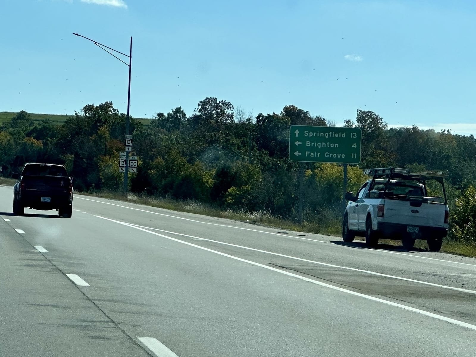 A green sign beside the highway: Springfield 13 ahead, Brighton 4 and Fair Grove 11 to the left.