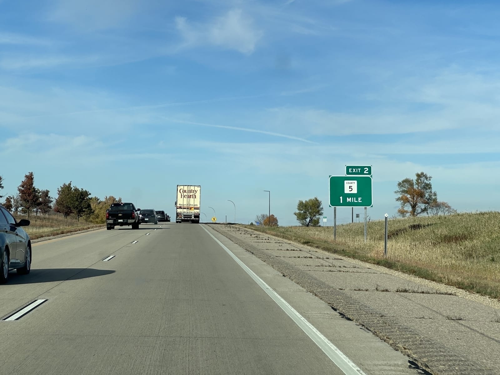 A green exit sign beside the highway: Exit 2, County 5, 1 mile.