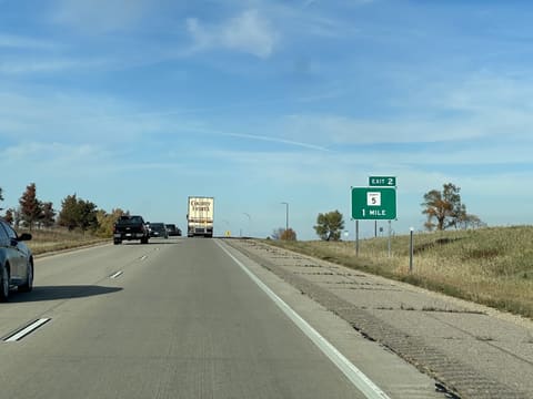 A green exit sign beside the highway: Exit 2, County 5, 1 mile.