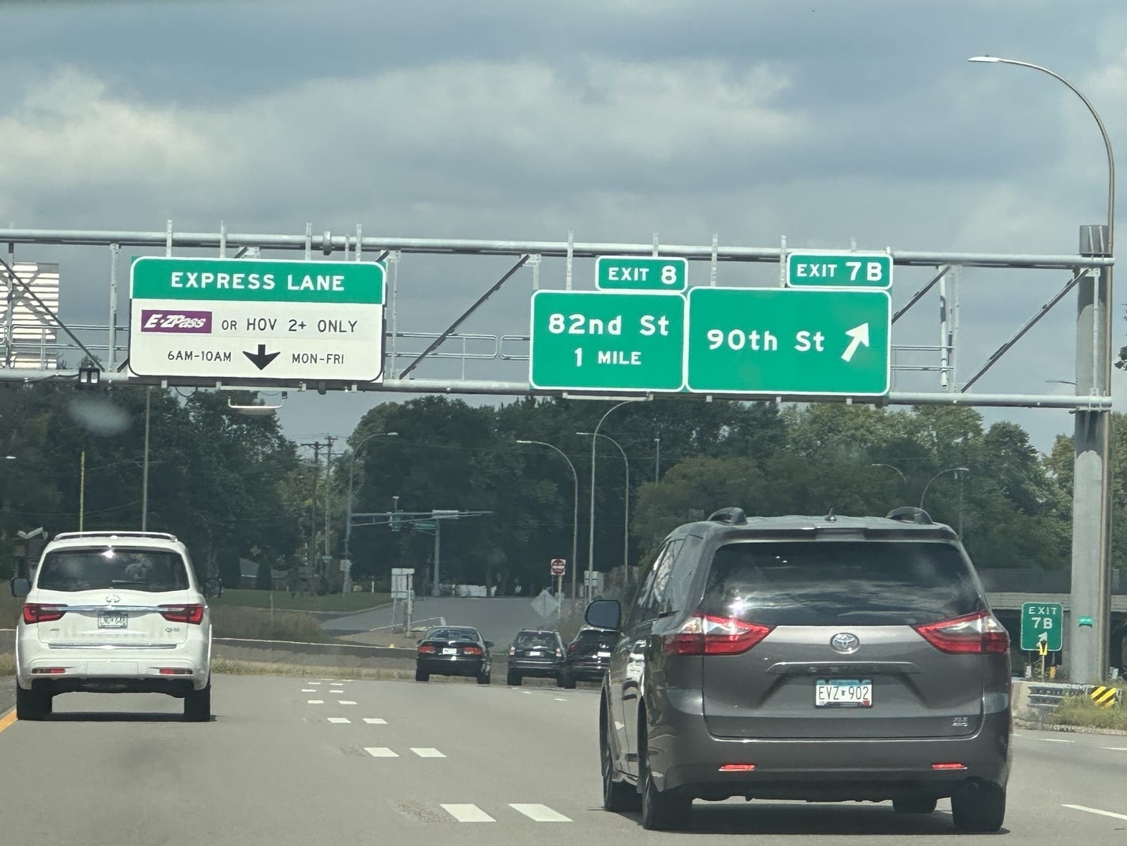 Overhead signs on I-35W: Express Lane (E-ZPass or HOV 2+ only, 6AM-10AM Mon-Fri), Exit 8 82nd St 1 mile, and Exit 7B 90th St.